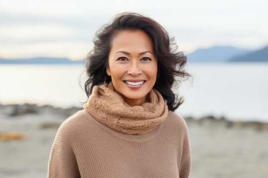 Lifestyle portrait of a Indonesian woman in her 40s in a beach background wearing a cozy sweater