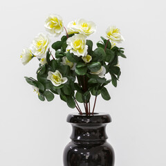 Artificial flowers in a black vase. Close up. On a white background