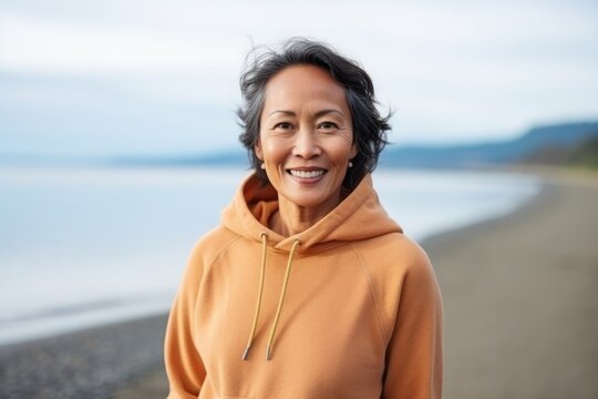 Medium shot portrait of a Indonesian woman in her 50s in a beach background wearing a cozy sweater