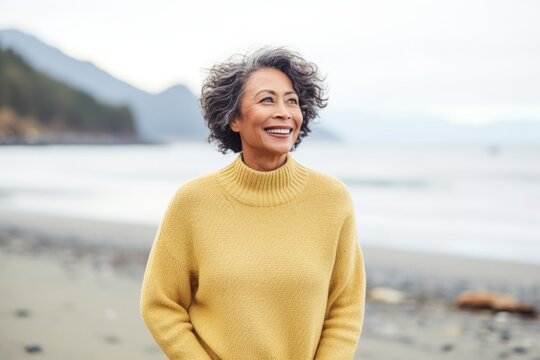 Medium shot portrait of a Indonesian woman in her 50s in a beach background wearing a cozy sweater