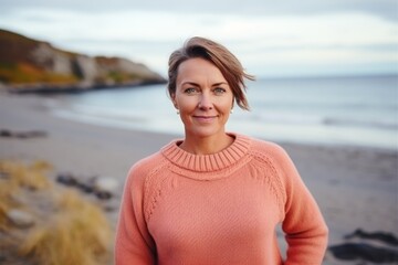 Medium shot portrait of a Russian woman in her 40s in a beach background wearing a cozy sweater