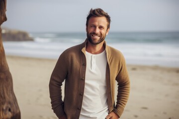 Lifestyle portrait of a Russian man in his 30s in a beach background wearing a chic cardigan