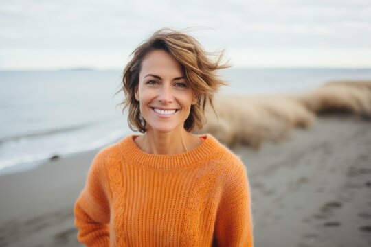 Medium shot portrait of a Russian woman in her 40s in a beach background wearing a cozy sweater