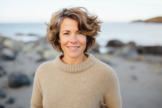 Lifestyle portrait of a Russian woman in her 40s in a beach background wearing a cozy sweater