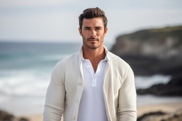 Lifestyle portrait of a Brazilian man in his 30s in a beach background wearing a chic cardigan