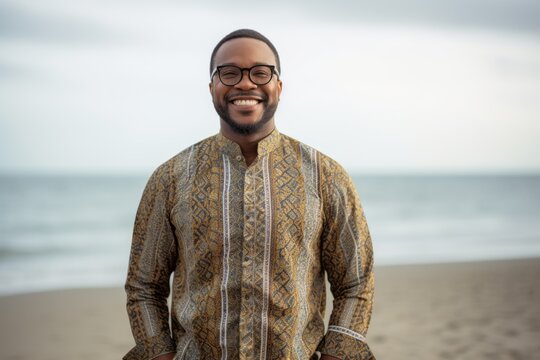 Lifestyle portrait of a Nigerian man in his 40s in a beach background wearing a chic cardigan