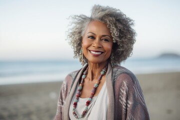 Lifestyle portrait of a Nigerian woman in her 60s in a beach background wearing a chic cardigan