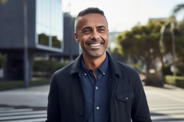 Obraz premium Portrait of handsome mature African man smiling and looking at camera outdoors