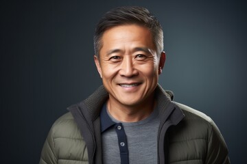 Fototapeta premium Portrait of a happy asian man looking at camera against grey background