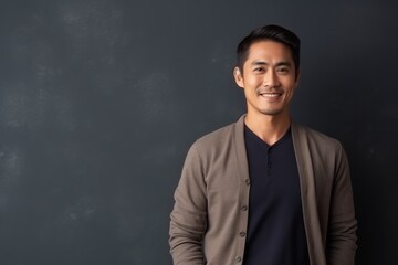 Fototapeta premium Portrait of a happy young asian man standing against black background