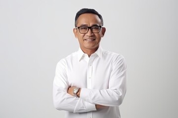Portrait of confident asian man in eyeglasses standing with arms crossed over white background
