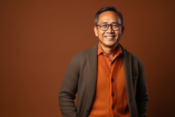 Fototapeta premium Portrait of Indian asian senior man wearing eyeglasses against brown background