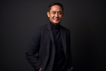 Portrait of young handsome Asian businessman against black backgroun