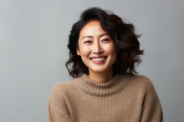 Portrait of a Chinese woman in her 40s in a white background wearing a cozy sweater