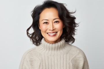 Fototapeta premium Portrait of a Chinese woman in her 40s in a white background wearing a cozy sweater