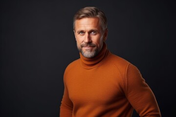 Fototapeta na wymiar Portrait of handsome mature man in orange sweater on black background.