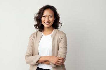 Portrait of a smiling asian businesswoman standing with arms crossed over white background