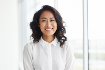 Portrait of smiling young businesswoman standing in office, looking at camera.
