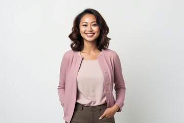 Portrait of a smiling businesswoman standing with hands in pockets over white background