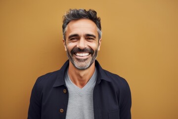 Fototapeta premium Portrait of a handsome middle-aged man smiling against brown background