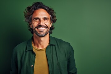 Fototapeta premium Portrait of a handsome young man smiling at camera while standing against green background
