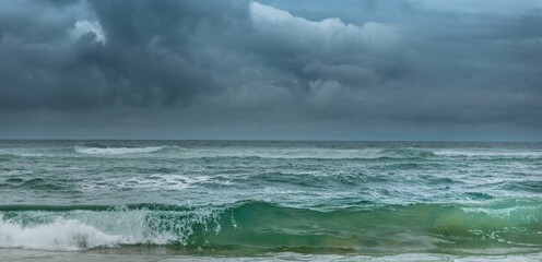 Green wave breaking under dark cloudy skies with a storm approaching