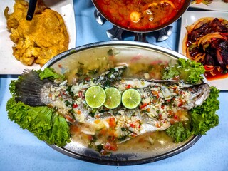 a plate with fish, chili and another dish on a table