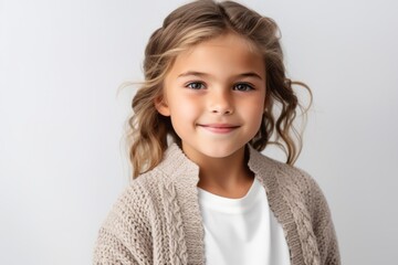 portrait of smiling little girl in beige sweater isolated on grey