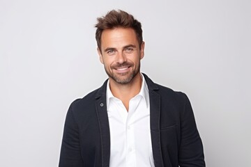 Portrait of handsome young man looking at camera and smiling while standing against white background
