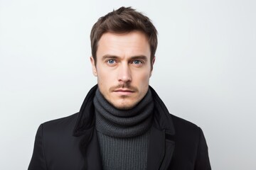 Obraz premium Portrait of handsome young man in black coat and scarf on white background