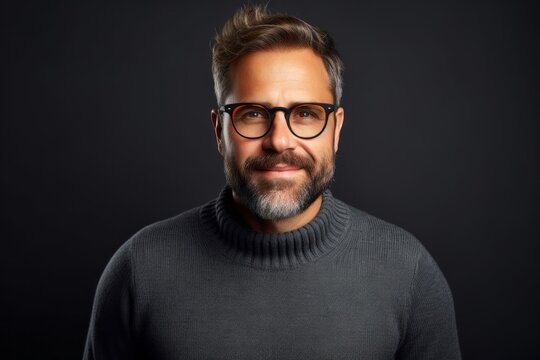 Portrait of a handsome bearded man in glasses on a black background