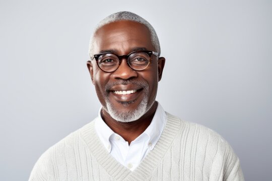 Portrait of a Nigerian man in his 50s in a white background wearing a chic cardigan