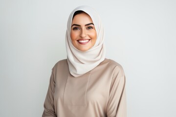 Portrait of a Saudi Arabian woman in her 30s in a white background wearing a cozy sweater