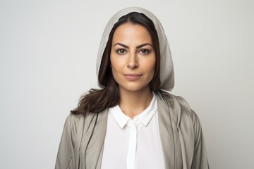 Medium shot portrait of a Saudi Arabian woman in her 40s in a white background wearing a chic cardigan