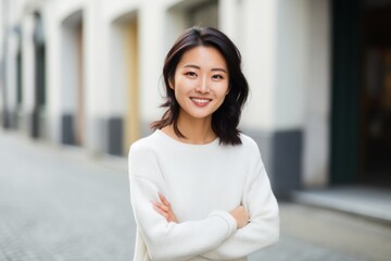 Smiling asian woman standing with arms crossed in the city street