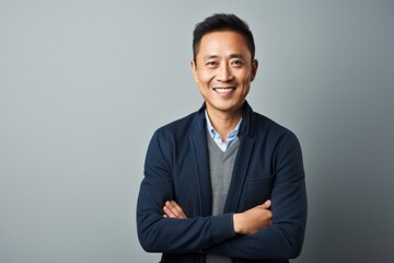 Portrait of smiling asian man with crossed arms against grey background