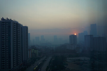 Morning sun rising above the skyscrapers in Hanoi foggy sky