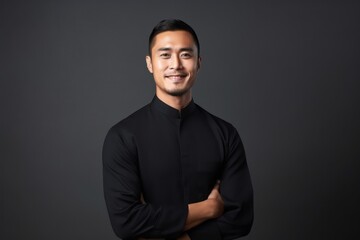 Obraz premium Portrait of a happy young asian man with arms crossed on black background