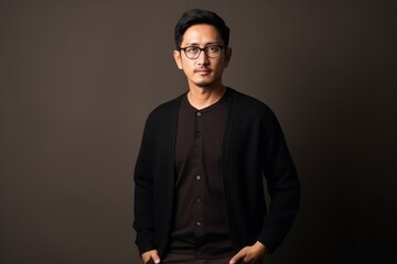 Obraz premium Portrait of a confident young Asian man wearing glasses against gray background