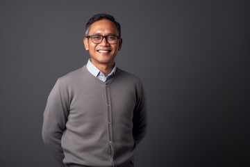 Portrait of a happy asian man in eyeglasses against grey background
