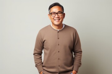 Obraz premium Portrait of a happy young asian man standing against gray background