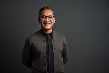 Fototapeta premium Portrait of a happy mature Indian man in eyeglasses against grey background