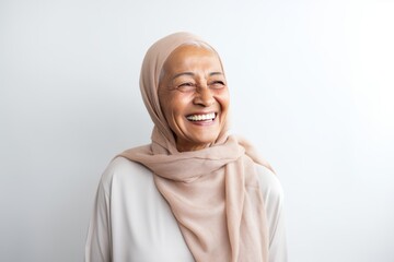 Portrait of happy senior muslim woman smiling at camera against white background