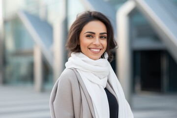 Portrait of a Saudi Arabian woman in her 30s in a modern architectural background wearing a chic cardigan