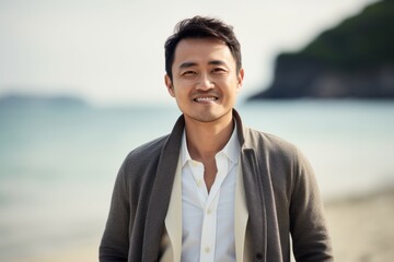 Portrait of handsome asian man smiling on the beach at sunset