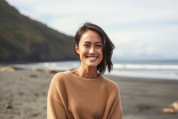 Portrait of a smiling young woman standing on the beach in autumn