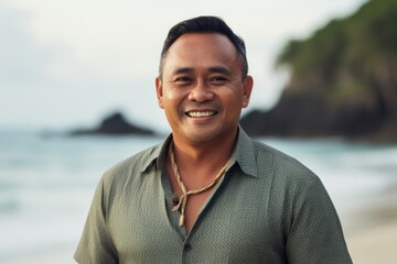 Portrait of a smiling asian man standing on the beach at sunset