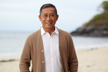 Portrait of a happy mature man standing on the beach and looking at camera
