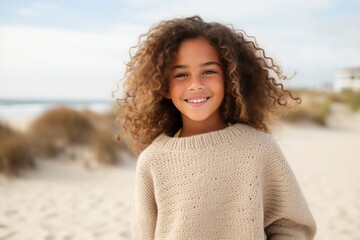 Portrait of a smiling young girl with curly hair on the beach