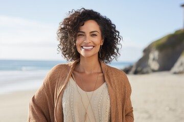 Portrait of smiling young woman standing on beach at the seaside